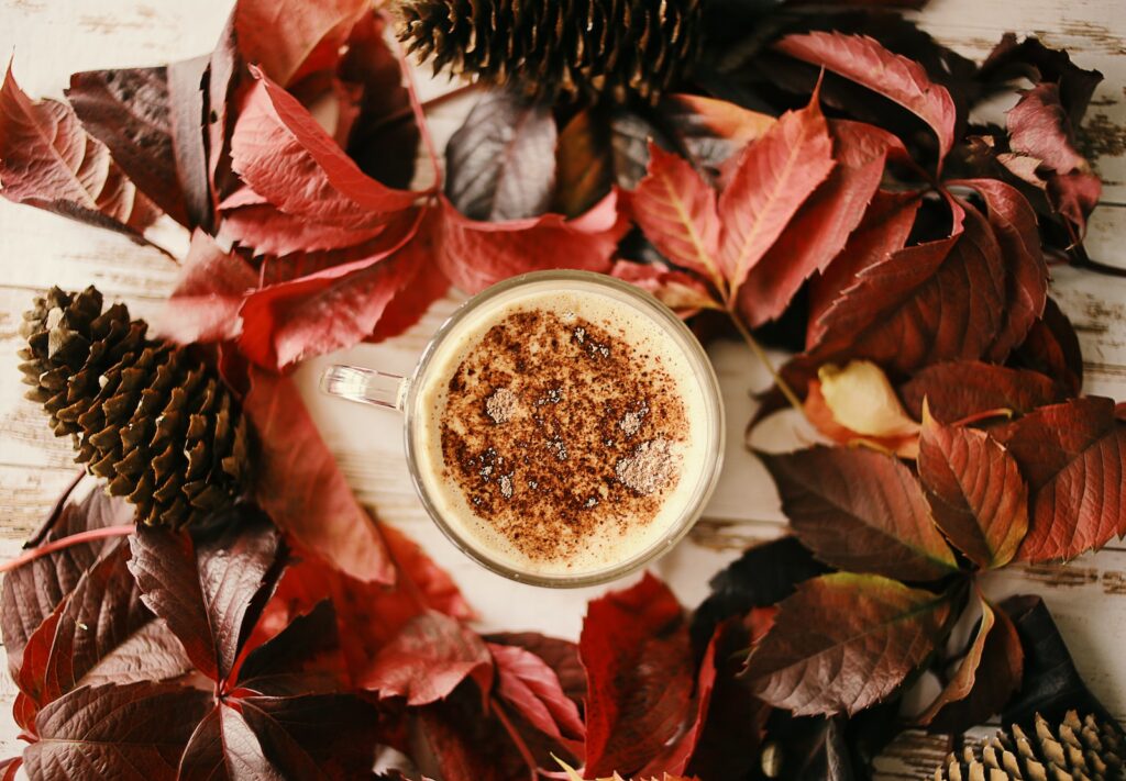 white ceramic mug with coffee on red leaves