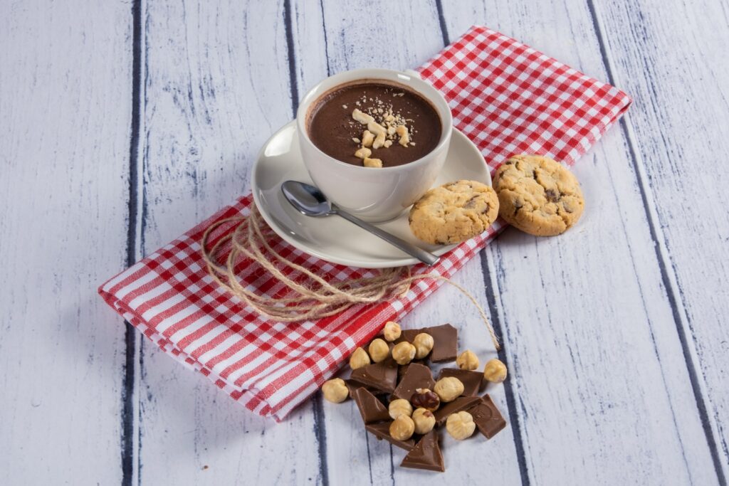 a cup of hot chocolate and cookies on a red and white checkered napkin