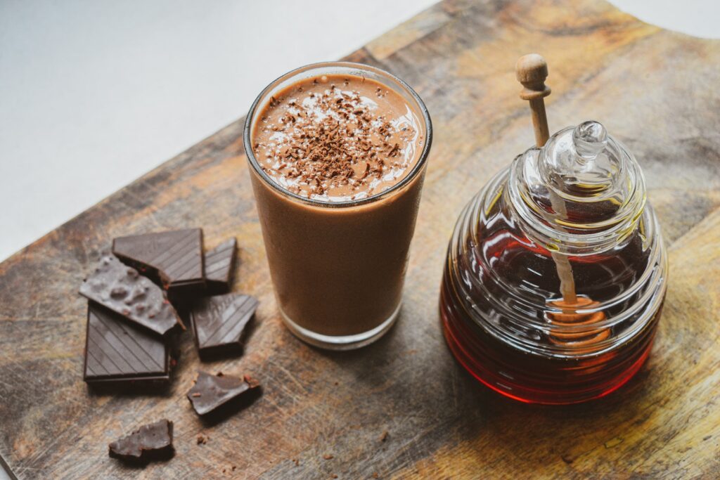 a glass of hot chocolate next to a jar of chocolate