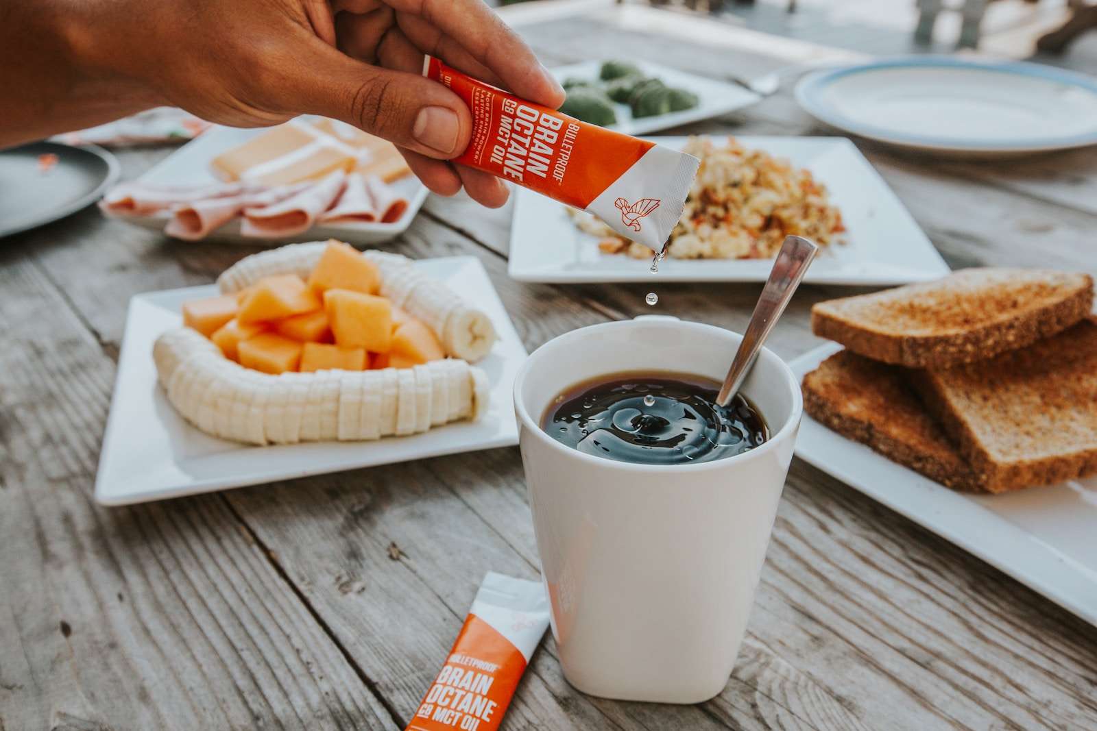 Keto Coffee a person holding a carton of milk over a cup of coffee