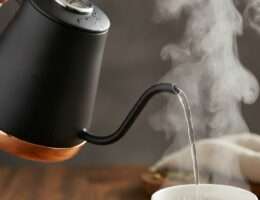 Gooseneck kettle pouring hot water with steam