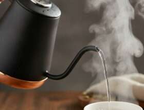 Gooseneck kettle pouring hot water with steam